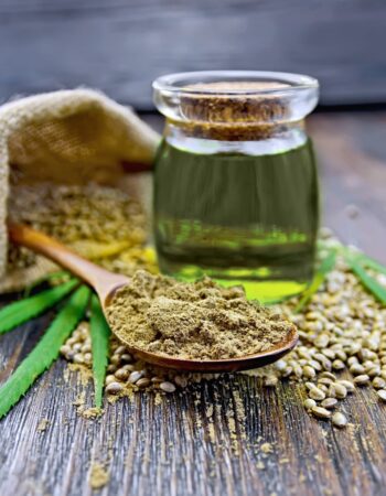 hemp-flour-in-bowl-seed-in-bag-on-the-table-oil-of-cannabis-in-glass-jar-green-leaves-on-the-background-of-wooden-boards