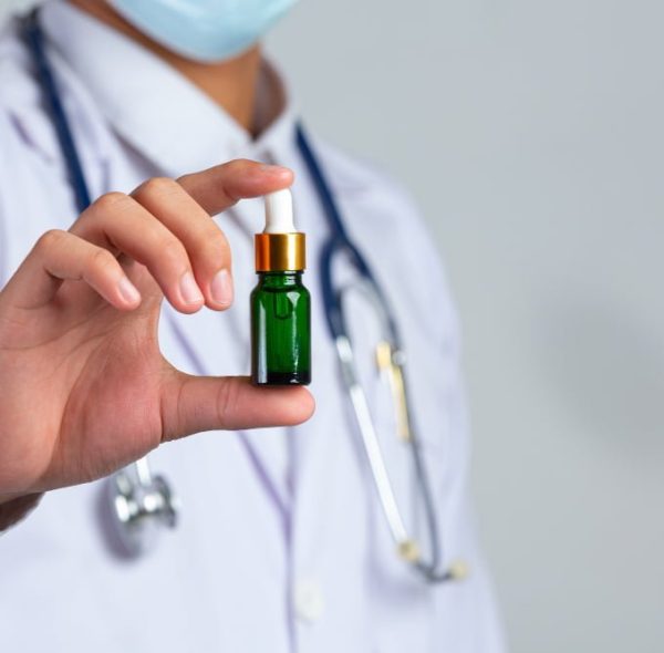 close-up-picture-of-medical-doctor-holding-bottle-of-cannabis-oil-on-white-wall close-up-picture-of-medical-doctor-holding-bottle-of-cannabis-oil-on-white-wall